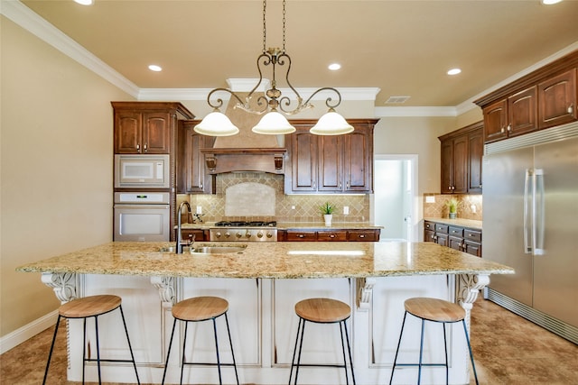 kitchen featuring pendant lighting, sink, a large island, built in appliances, and a notable chandelier