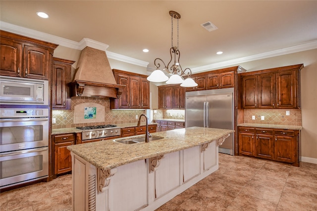 kitchen with built in appliances, a breakfast bar area, sink, a center island with sink, and premium range hood