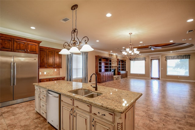 kitchen featuring an island with sink, ceiling fan with notable chandelier, pendant lighting, stainless steel appliances, and sink