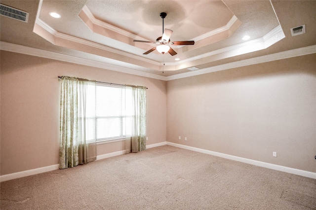 empty room with a tray ceiling, ceiling fan, carpet flooring, and crown molding