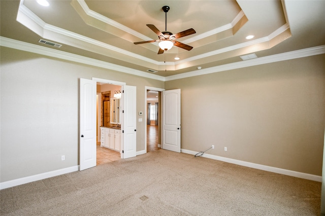 unfurnished bedroom featuring ceiling fan, a raised ceiling, ensuite bathroom, and crown molding