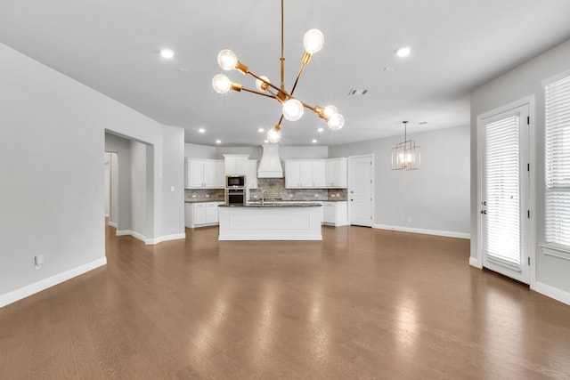 kitchen with white cabinets, a center island with sink, appliances with stainless steel finishes, and dark wood-type flooring