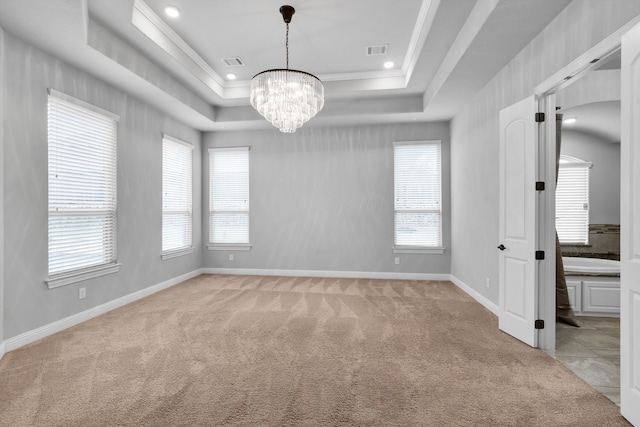 empty room featuring a raised ceiling, crown molding, and light colored carpet