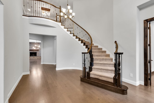 stairs with wood-type flooring, a towering ceiling, and an inviting chandelier