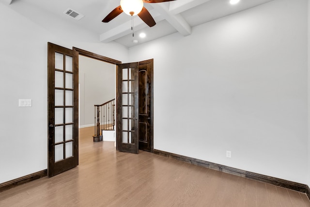 empty room featuring light wood-type flooring, ceiling fan, beamed ceiling, and french doors