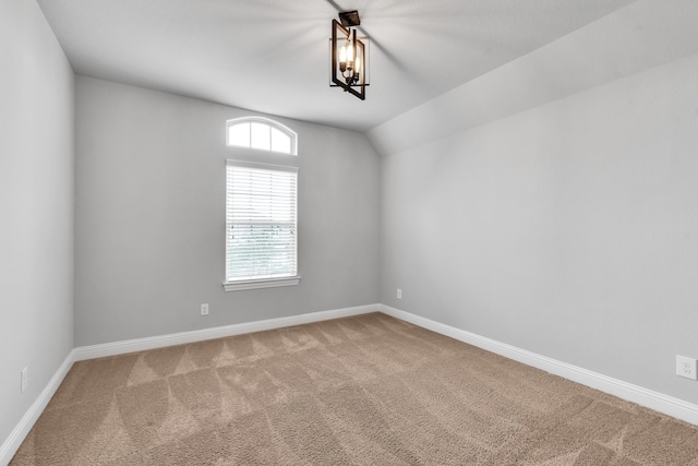 carpeted spare room with vaulted ceiling