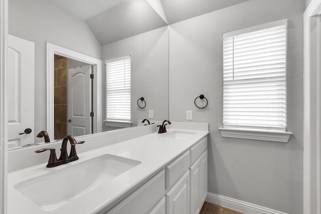 bathroom featuring lofted ceiling, a textured ceiling, plenty of natural light, and vanity