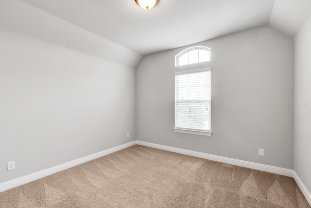 carpeted empty room with vaulted ceiling