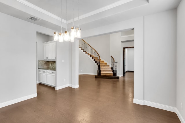 unfurnished room featuring a notable chandelier, a tray ceiling, and dark wood-type flooring