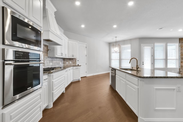 kitchen featuring dark hardwood / wood-style floors, a kitchen island with sink, sink, white cabinets, and stainless steel appliances