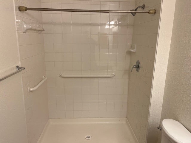 bathroom with a tile shower and toilet