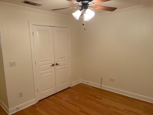 empty room featuring crown molding, hardwood / wood-style floors, and ceiling fan