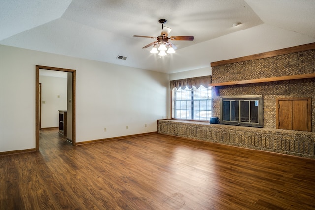 unfurnished living room with ceiling fan, a brick fireplace, a textured ceiling, dark hardwood / wood-style floors, and vaulted ceiling