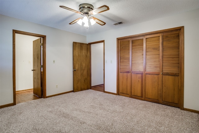 unfurnished bedroom with ceiling fan, light colored carpet, and a textured ceiling