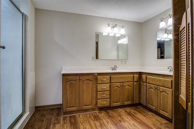 bathroom with an enclosed shower, hardwood / wood-style flooring, vanity, and a textured ceiling