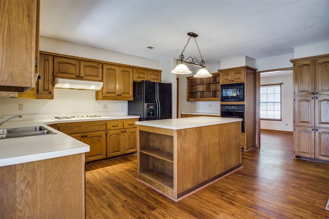 kitchen with pendant lighting, black appliances, a center island, and dark hardwood / wood-style flooring