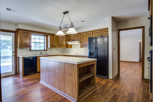 kitchen featuring pendant lighting, dark wood-type flooring, sink, a kitchen island, and black appliances