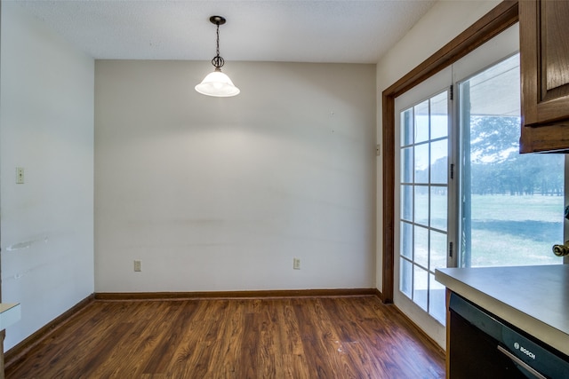 unfurnished dining area featuring a textured ceiling and dark hardwood / wood-style floors