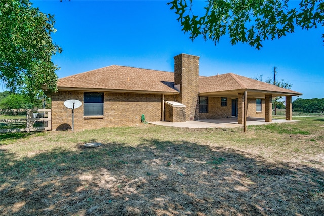 rear view of property featuring a lawn and a patio area