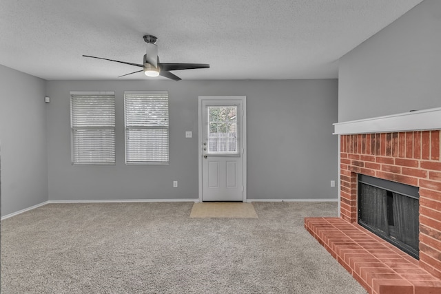 unfurnished living room with a textured ceiling, carpet, ceiling fan, and a brick fireplace