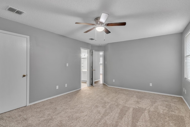 empty room featuring ceiling fan, light colored carpet, and a textured ceiling