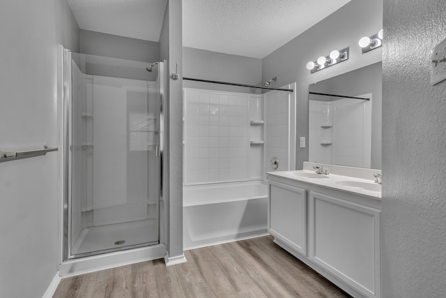 bathroom with independent shower and bath, vanity, hardwood / wood-style floors, and a textured ceiling