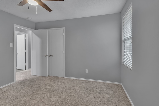 unfurnished room with ceiling fan, light colored carpet, and a textured ceiling