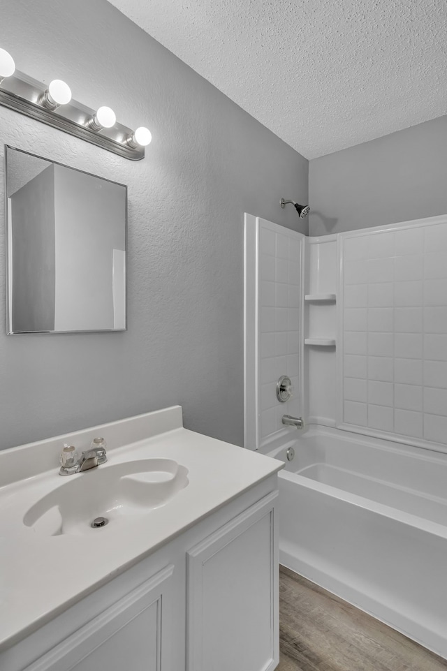 bathroom with  shower combination, hardwood / wood-style flooring, vanity, and a textured ceiling