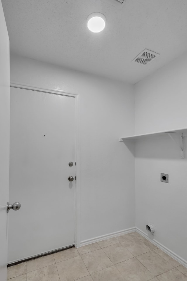 clothes washing area featuring electric dryer hookup and light tile patterned floors