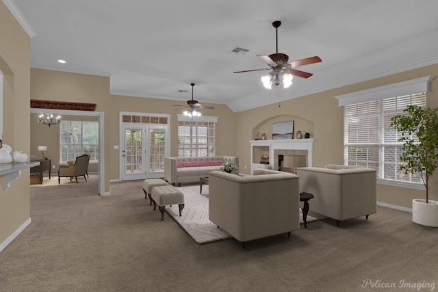 living room featuring a wealth of natural light, ornamental molding, carpet floors, and ceiling fan with notable chandelier