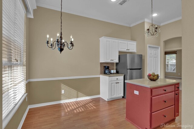 kitchen with an inviting chandelier, ornamental molding, white cabinets, and light hardwood / wood-style floors