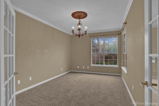 spare room with an inviting chandelier, crown molding, french doors, and carpet