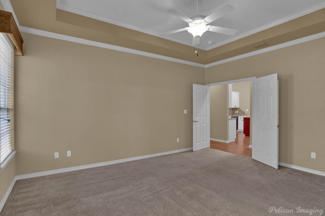 carpeted empty room featuring ceiling fan, ornamental molding, and a tray ceiling