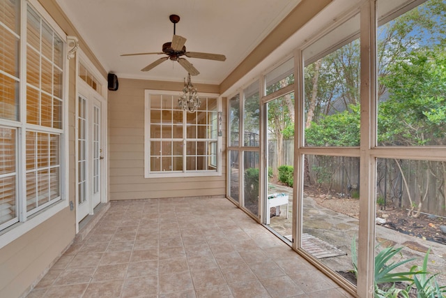 unfurnished sunroom with ceiling fan with notable chandelier