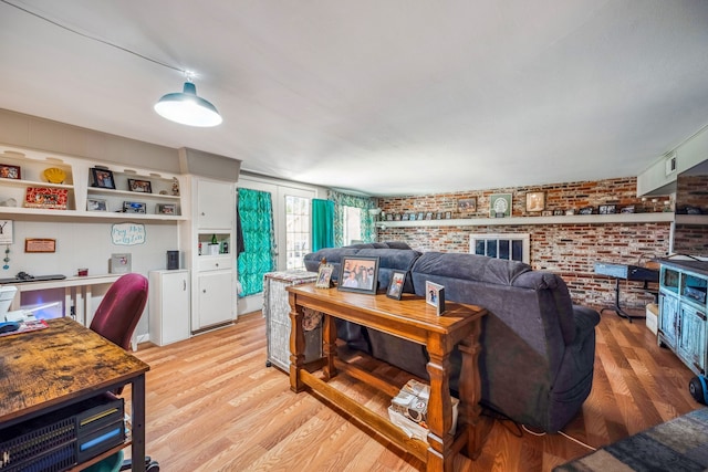 living room with brick wall and light hardwood / wood-style flooring