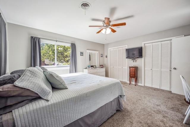 carpeted bedroom featuring ceiling fan and multiple closets