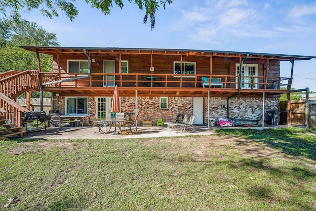 back of property featuring a lawn, a patio, and a wooden deck