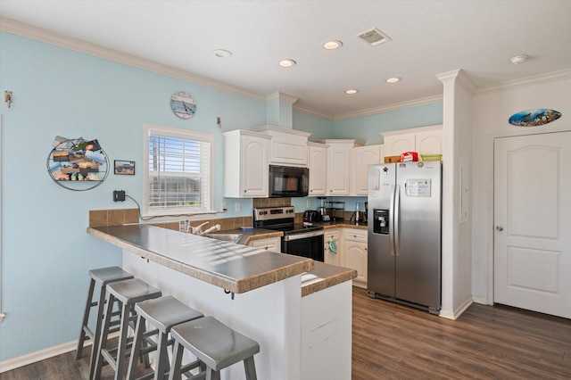 kitchen featuring white cabinets, ornamental molding, kitchen peninsula, dark wood-type flooring, and stainless steel appliances