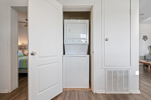 laundry room featuring ceiling fan, stacked washer / dryer, and dark hardwood / wood-style flooring