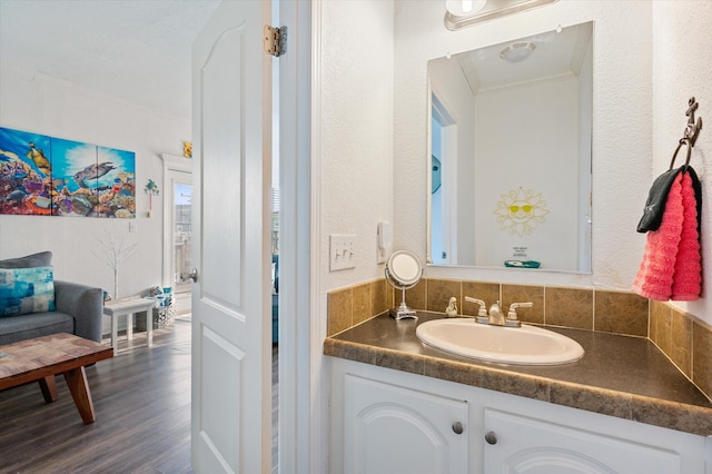 bathroom featuring ornamental molding, vanity, hardwood / wood-style floors, and tasteful backsplash