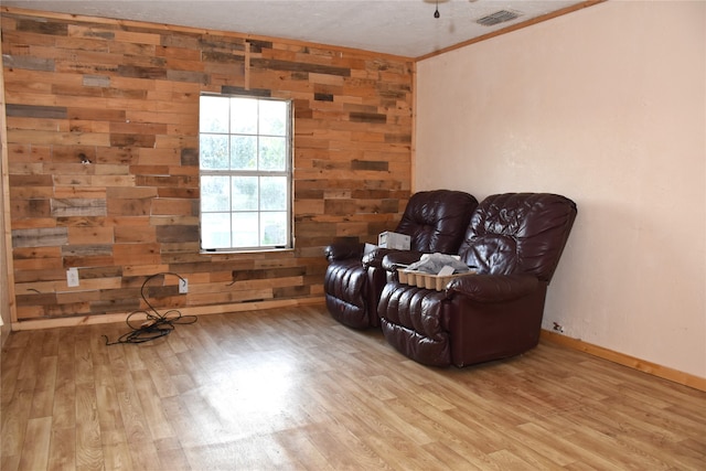 living area featuring ornamental molding, light hardwood / wood-style floors, and wooden walls