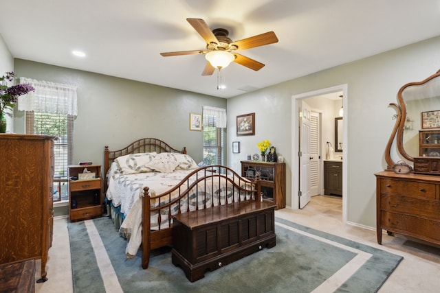 bedroom with light carpet, ensuite bathroom, and ceiling fan