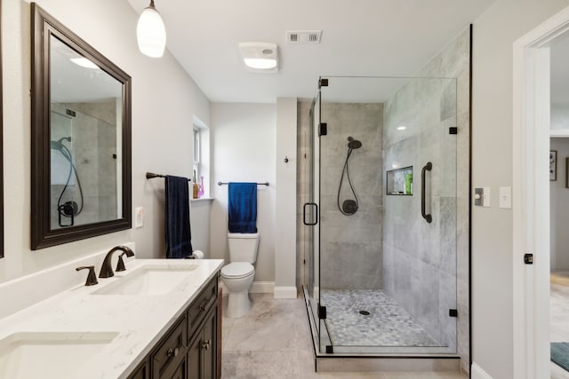 bathroom featuring toilet, vanity, and a shower with door