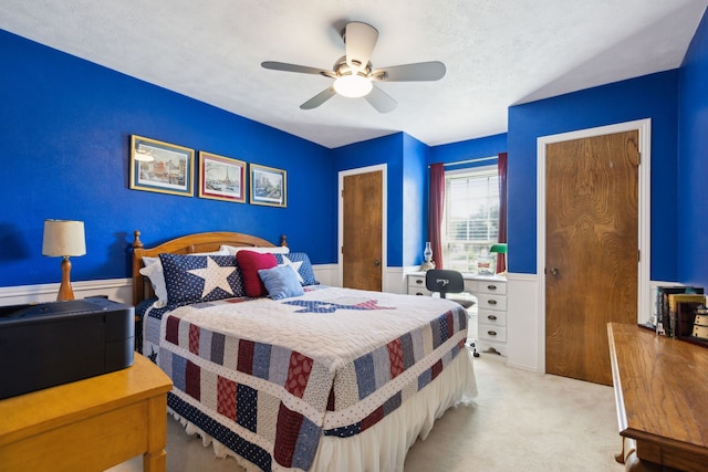 bedroom featuring a textured ceiling, light colored carpet, and ceiling fan