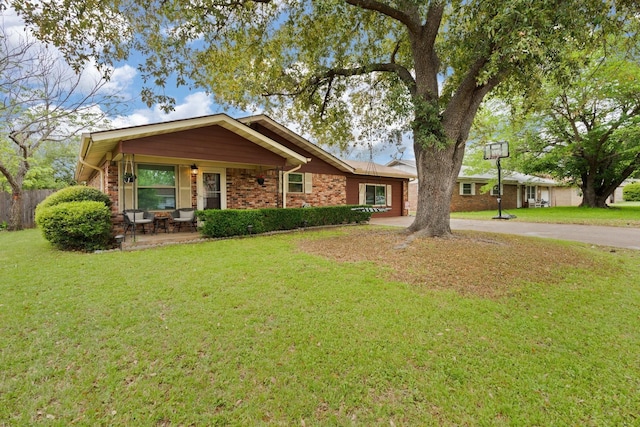 single story home with a porch, brick siding, driveway, and a front lawn