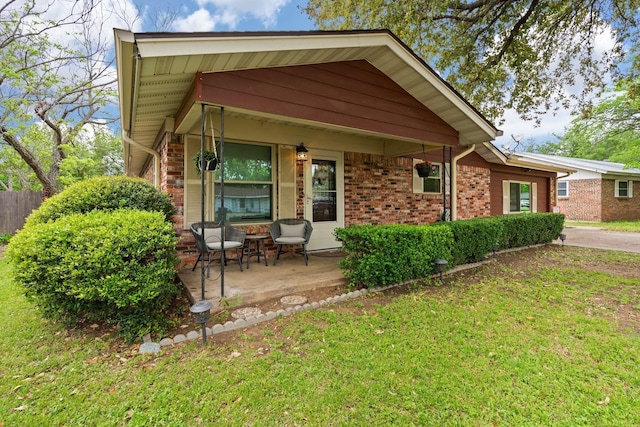 view of front facade with covered porch, brick siding, and a front lawn