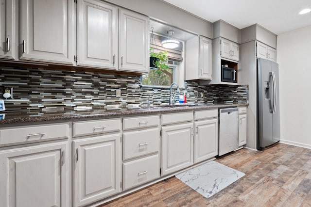 kitchen with stainless steel appliances, white cabinets, light hardwood / wood-style floors, and tasteful backsplash