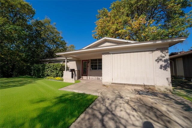 back of house with brick siding, a patio area, and a yard
