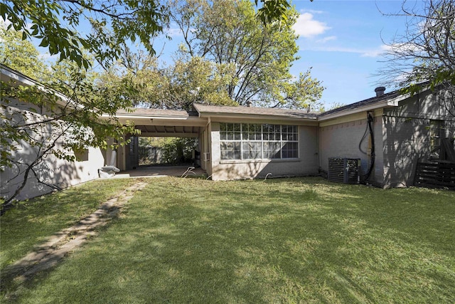 rear view of house featuring a lawn, cooling unit, and a carport