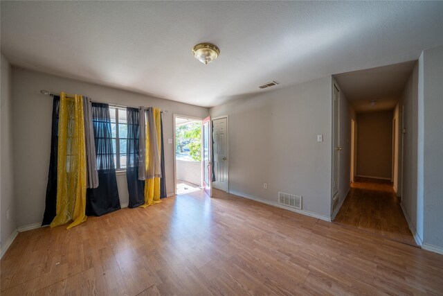 empty room featuring baseboards, wood finished floors, and visible vents